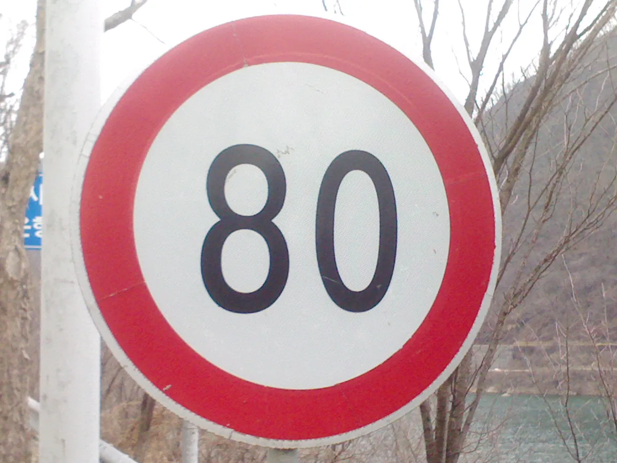 A round road sign showing a speed limit of 80.